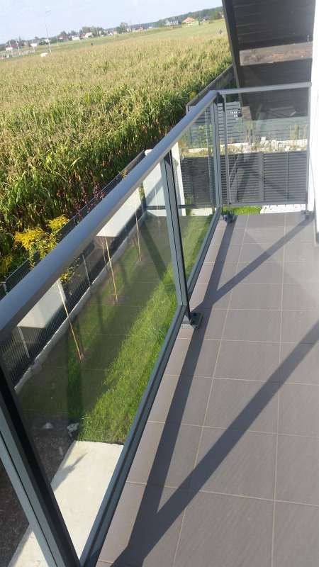 Ein Balkon mit Glasgeländer und Blick auf ein Feld.