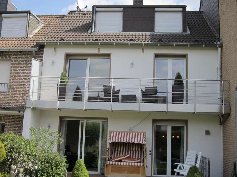 Die Rückseite eines Hauses mit Balkon und Stühlen