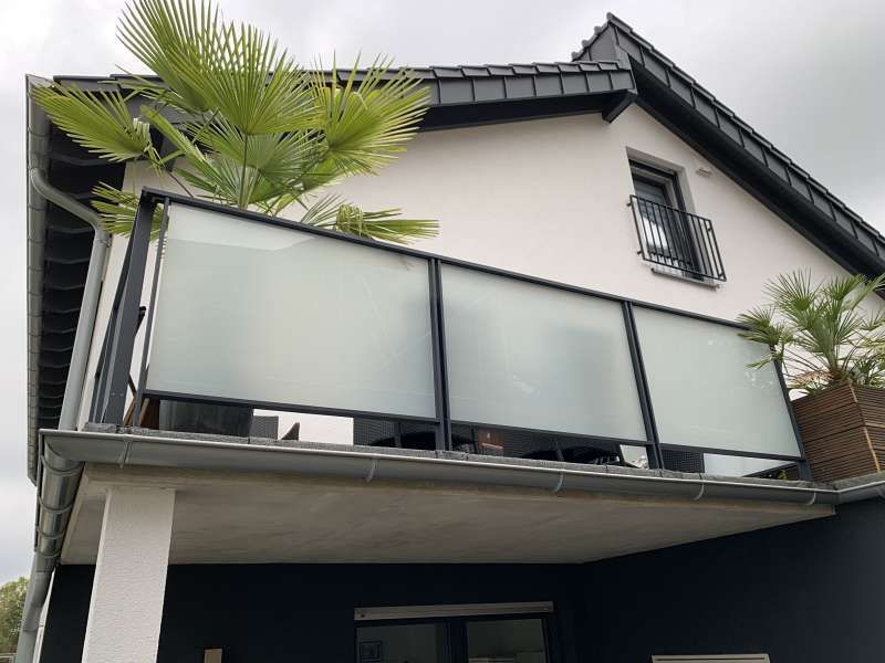 Ein Balkon an der Seite eines Hauses mit einer Palme im Hintergrund