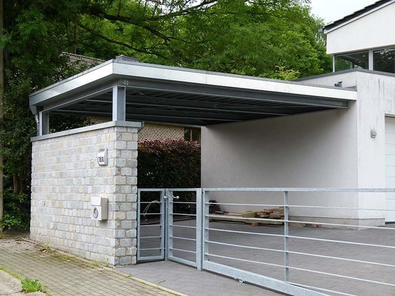 Ein weißes Haus mit Carport und Tor