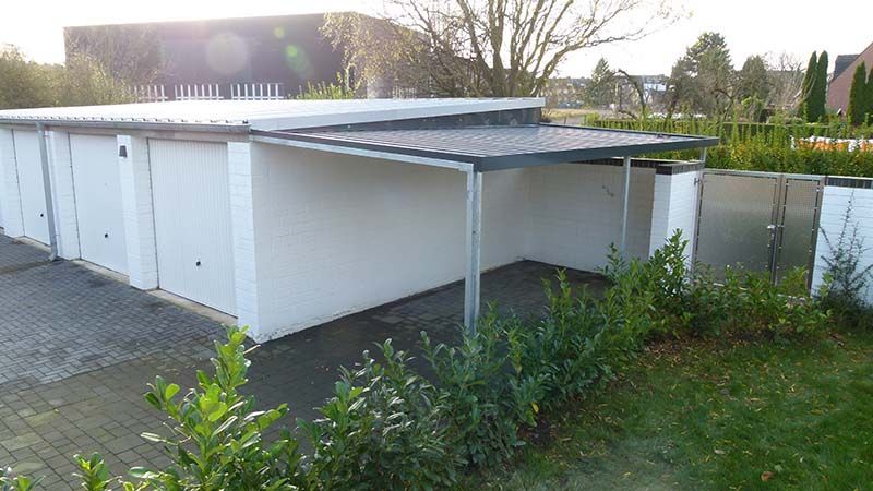 Eine weiße Garage mit einem Metalldach und einem Vordach.