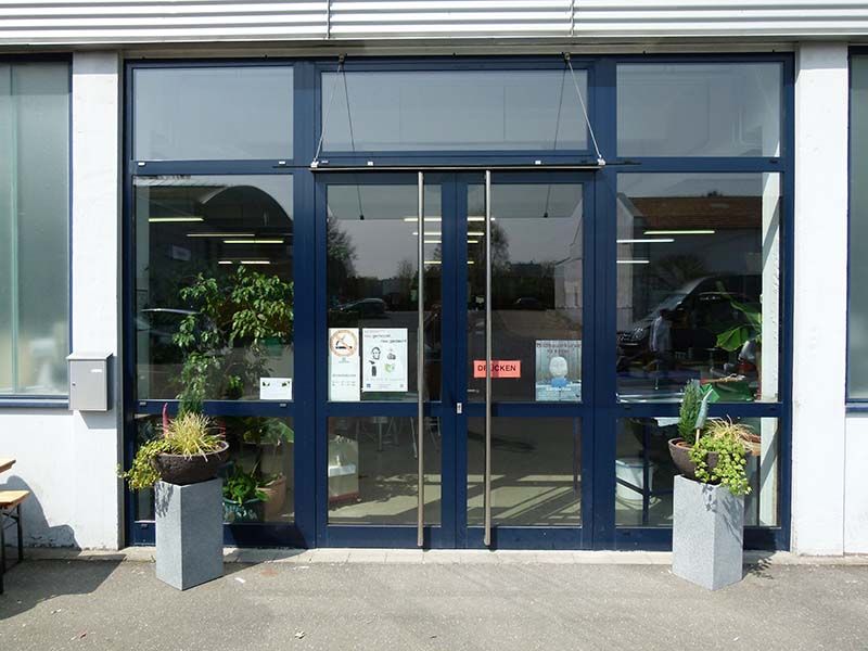 Ein Gebäude mit einer blauen Tür und Pflanzkübeln davor