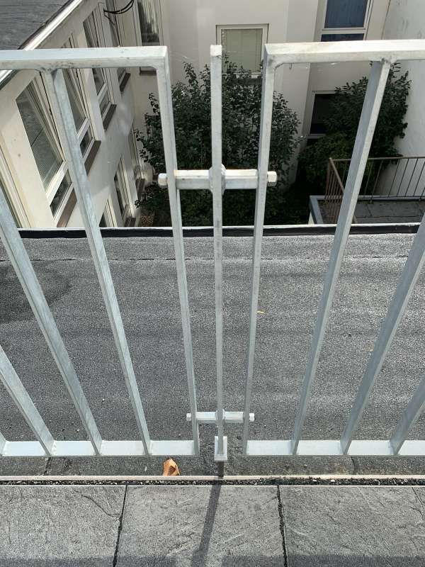 Ein weißes Geländer auf einem Balkon mit Blick auf ein Gebäude.
