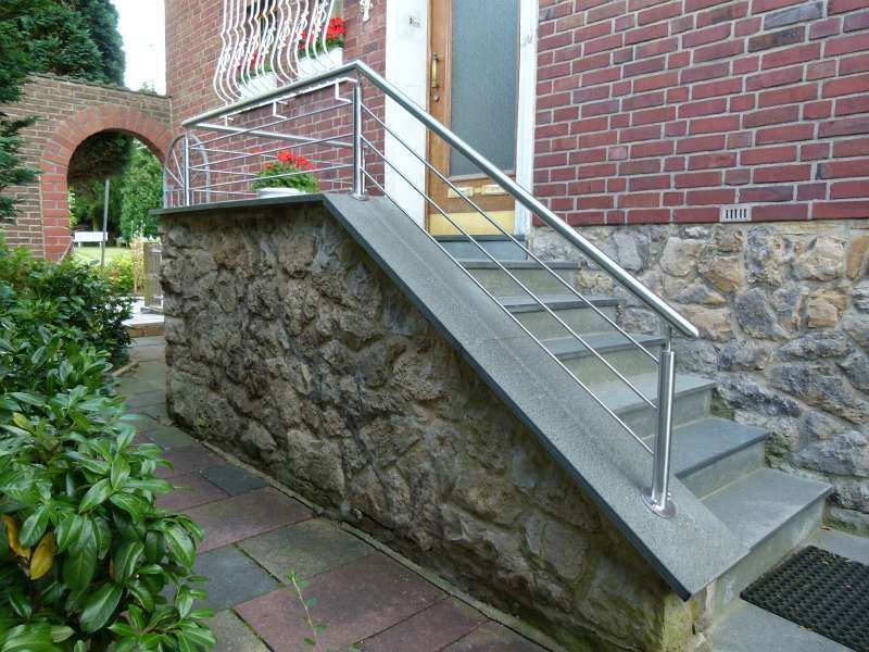 Eine Treppe, die zu einem Backsteingebäude mit einem Edelstahlgeländer hinaufführt.