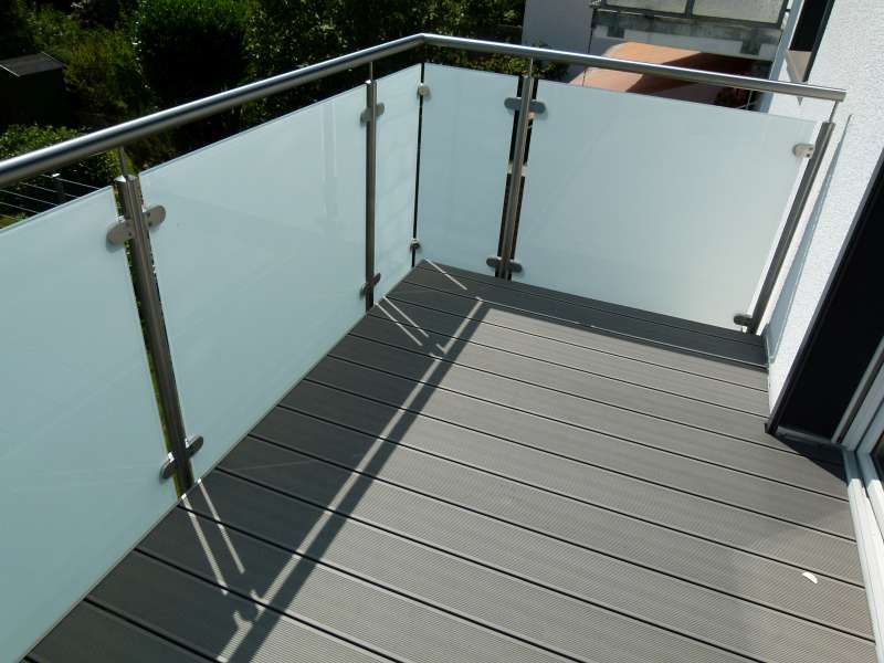 Ein Balkon mit Glasgeländer und Holzboden