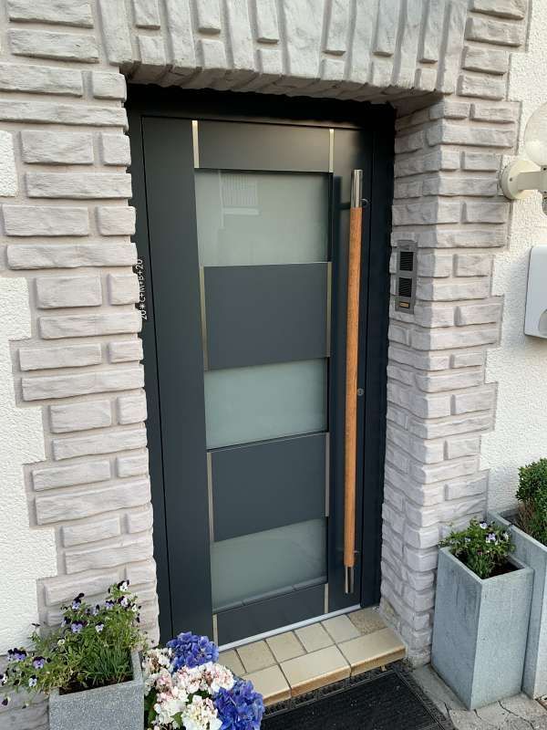 Eine Haustür mit einer Backsteinmauer und Blumen davor.