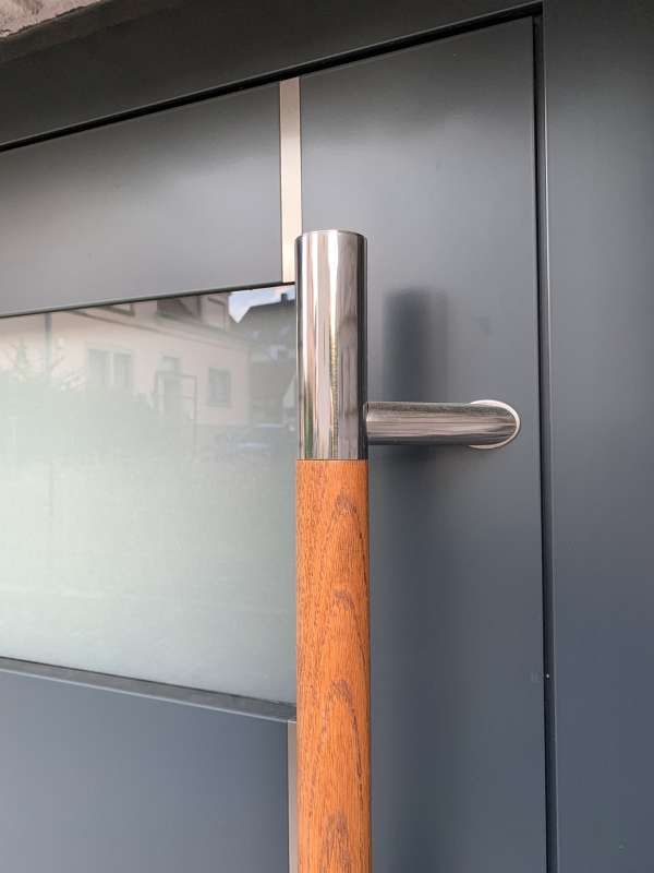 Eine Nahaufnahme einer Tür mit einem Holzgriff und einem Edelstahlgriff.