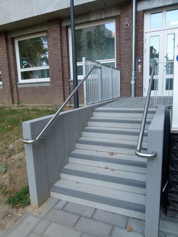 Eine Treppe, die zu einem Gebäude mit einem Edelstahlgeländer führt