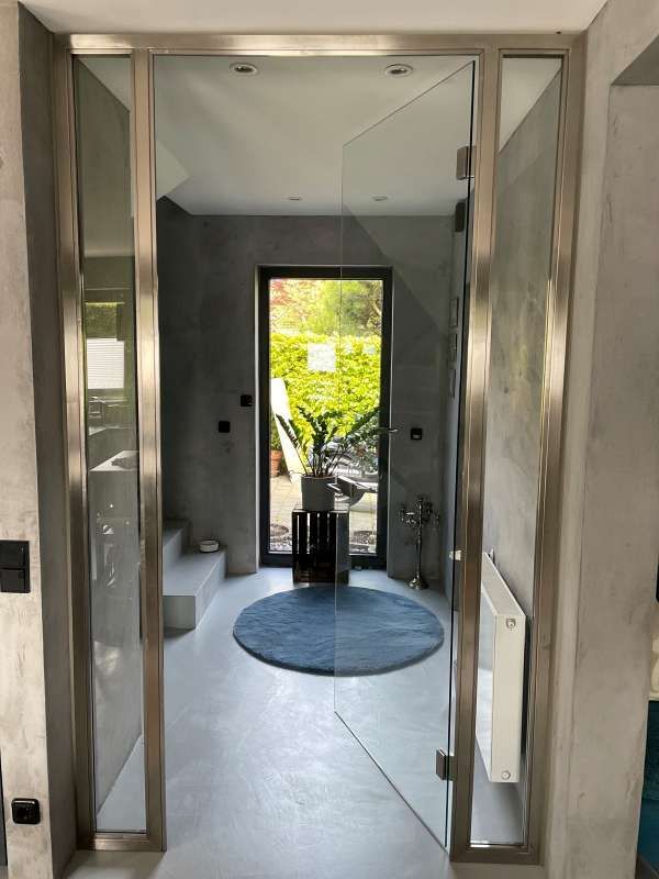 Ein Badezimmer mit Glastür und einem Teppich auf dem Boden