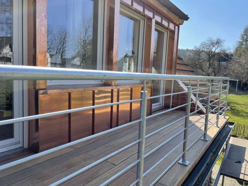 Ein Balkon mit Edelstahlgeländer und Holzterrasse.