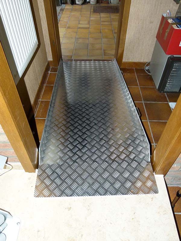 Eine Metallrampe führt zu einer Tür in einem Flur.