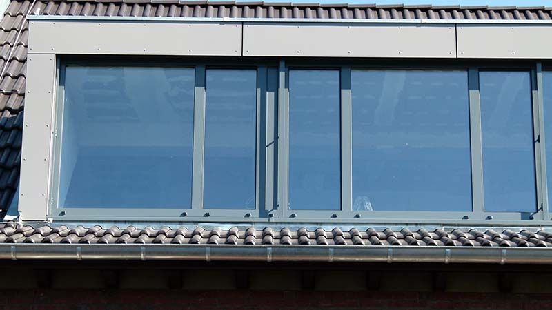 Ein großes Fenster an der Seite eines Gebäudes mit Ziegeldach.