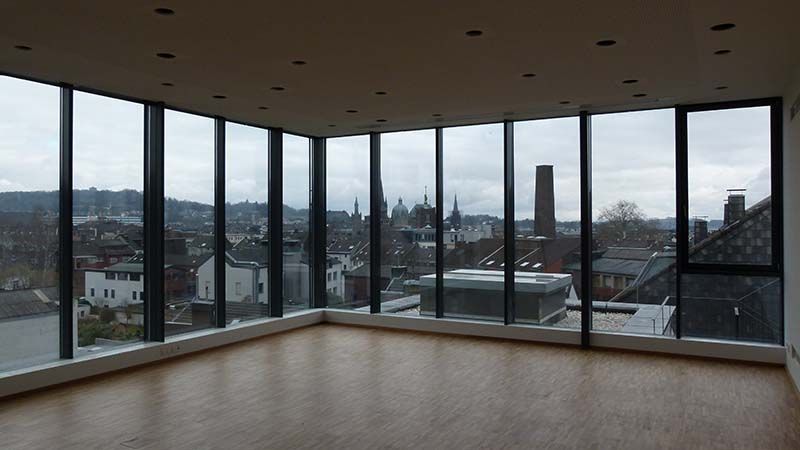 Ein leerer Raum mit vielen Fenstern und Blick auf eine Stadt