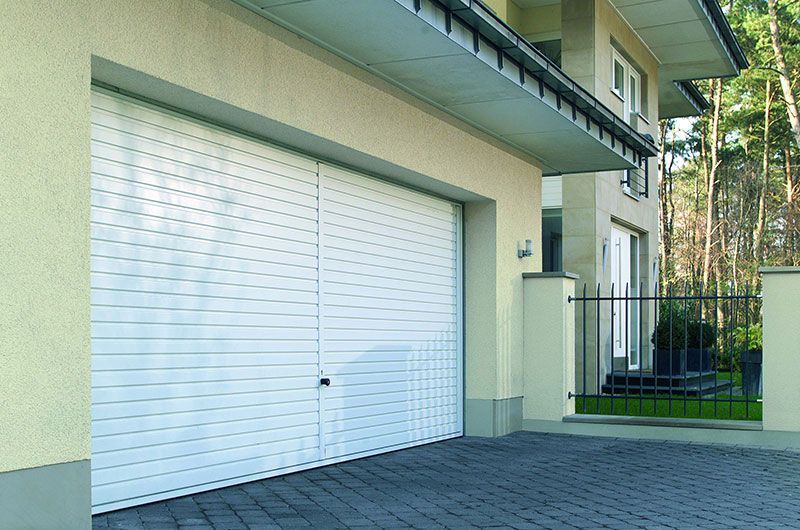 Vor einem Haus steht ein weißes Garagentor.