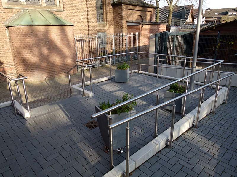 Ein Ziegelweg mit Edelstahlgeländer und Pflanzkübeln