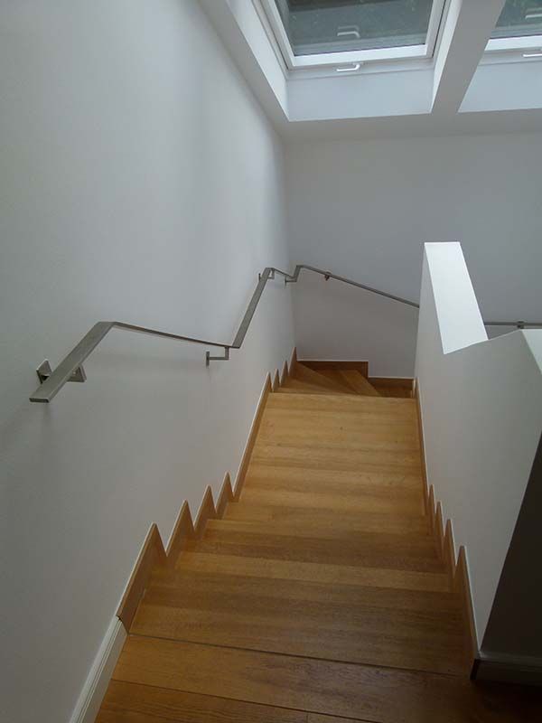 Eine Holztreppe mit Metallgeländer und Oberlicht.