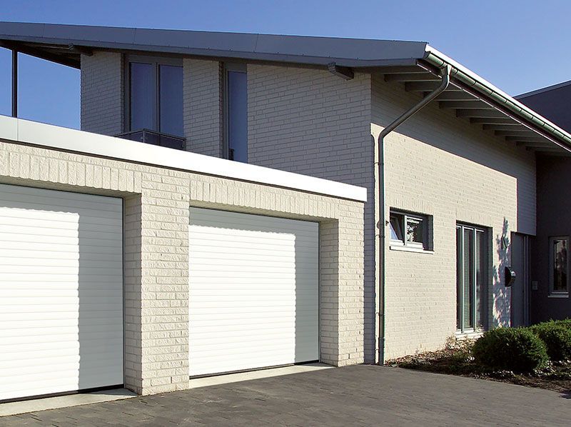 Ein Haus mit zwei Garagentoren und einer Einfahrt davor.