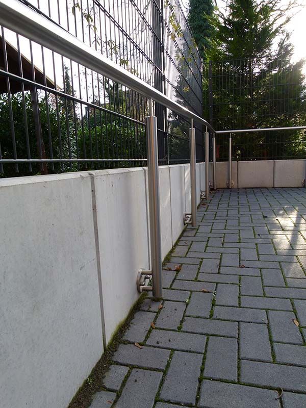 Ein gemauerter Gehweg mit einem Zaun im Hintergrund