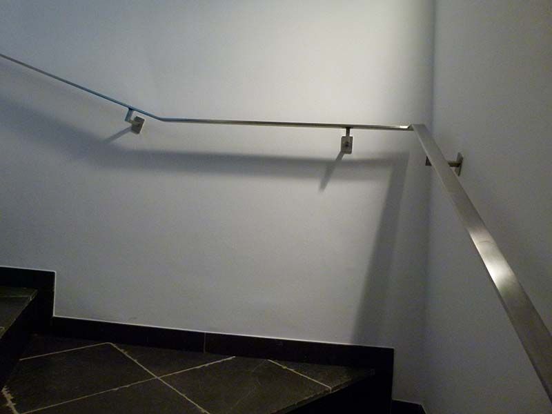 Eine Treppe mit Edelstahlgeländer und Fliesenboden