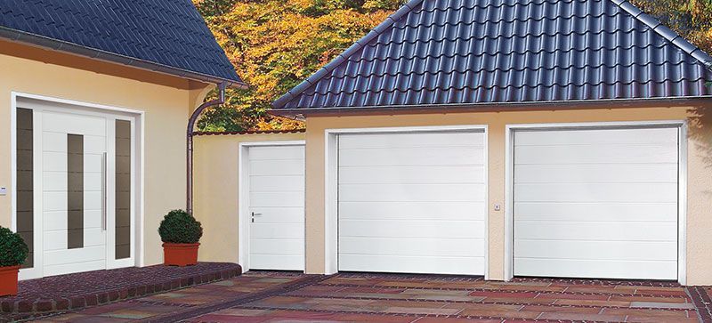 Eine Garage mit zwei weißen Garagentoren und einem blauen Dach.