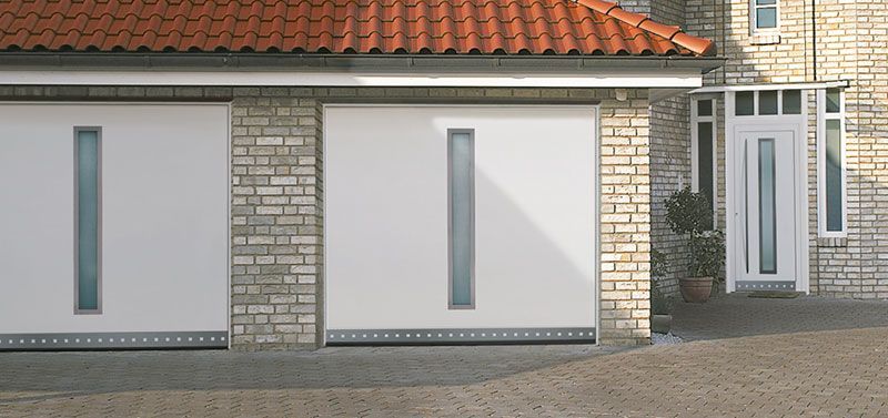 Ein Backsteinhaus mit weißen Garagentoren und einem roten Ziegeldach