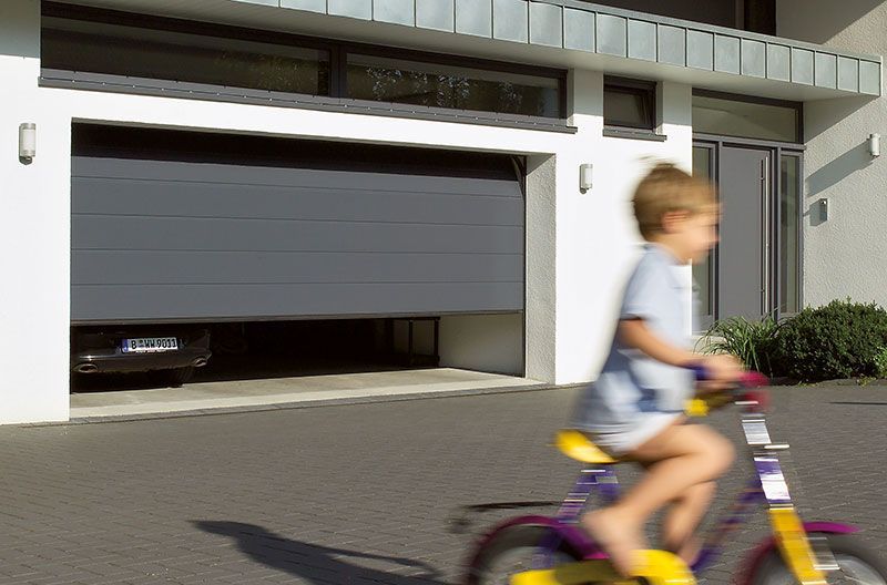 Ein Kind fährt Fahrrad vor einem Garagentor