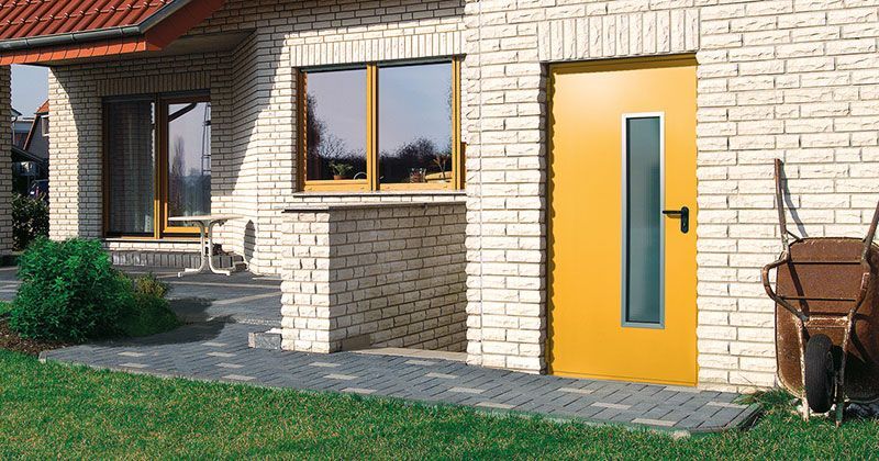 Ein weißes Backsteinhaus mit einer gelben Tür und einem Fenster.