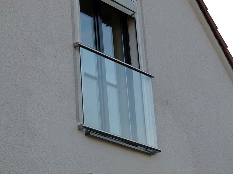 Ein Fenster mit einem Glasgeländer an der Seite eines Gebäudes