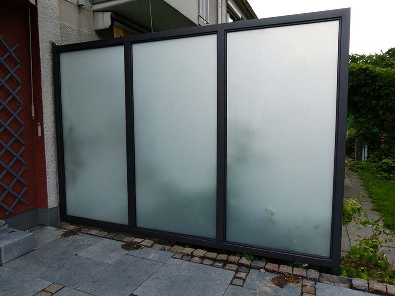 An der Seite eines Gebäudes steht ein Zaun aus Milchglas.