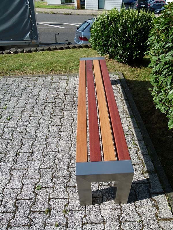 Eine Holzbank steht auf einem gemauerten Gehweg