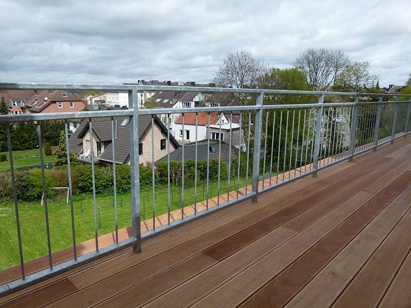 Eine Holzterrasse mit Metallgeländer mit Blick auf ein Wohngebiet