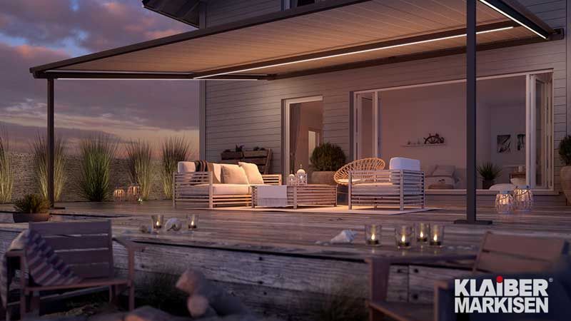 Eine Terrasse mit Pergola und vielen Möbeln darauf.