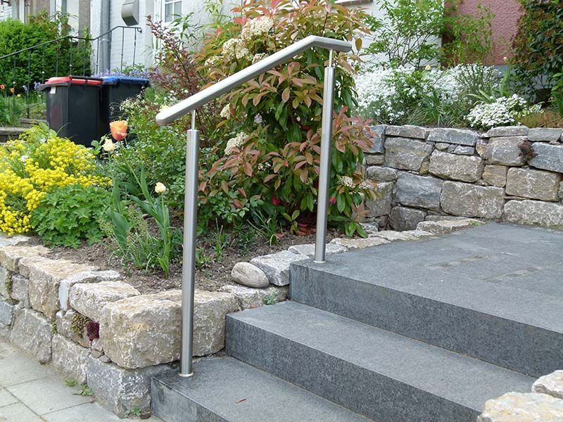 Eine Treppe mit einem Edelstahlgeländer und einer Steinmauer