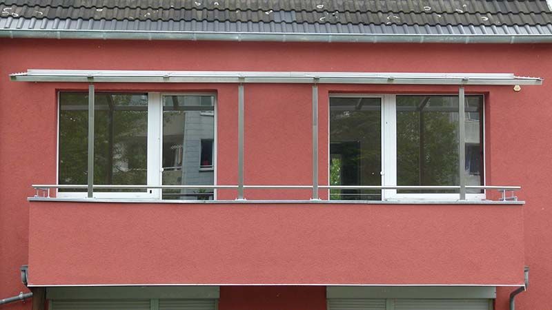 Ein rotes Gebäude mit einem Balkon und zwei Fenstern