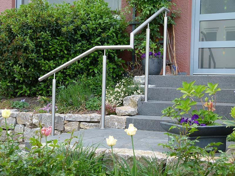Eine Treppe mit Edelstahlgeländer und Blumen davor