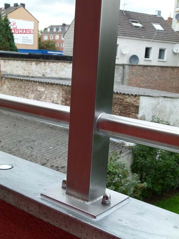 Ein Edelstahlgeländer mit einem Schild im Hintergrund, auf dem steht aachen