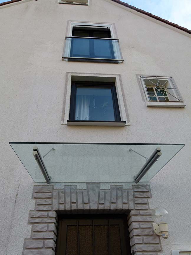 Ein weißes Gebäude mit einem Glasdach über der Tür