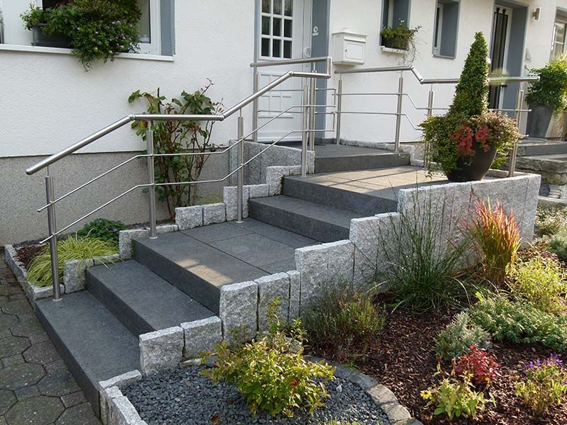 Eine Treppe, die zu einem Haus mit einem Edelstahlgeländer führt