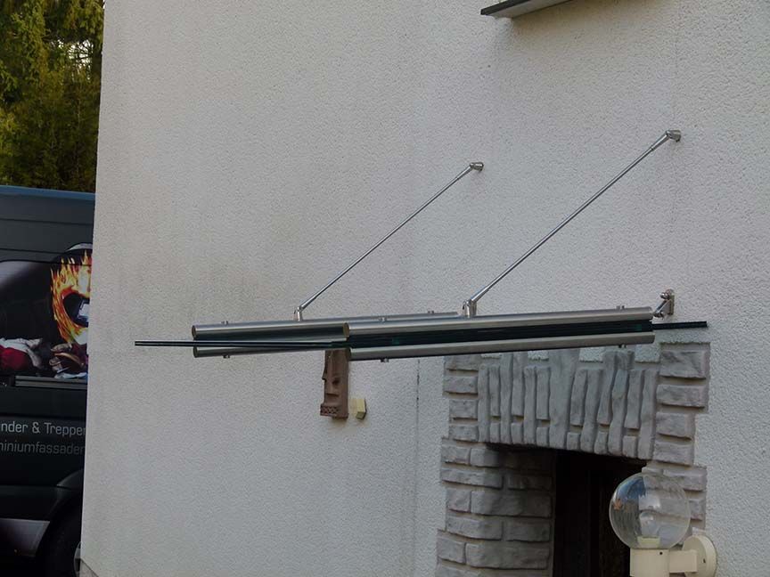 Ein weißes Gebäude mit einem Edelstahlvordach über einem Eingang