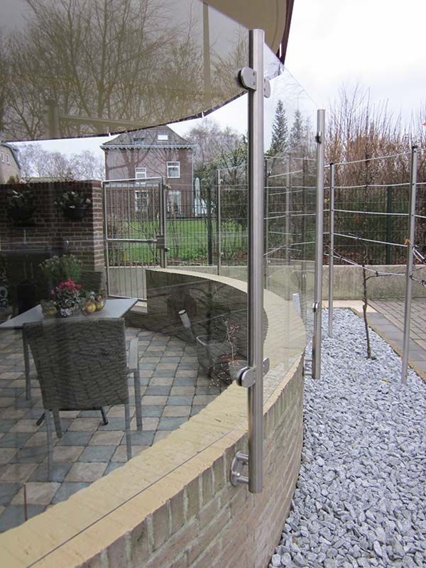 Eine Terrasse mit Tisch und Stühlen hinter einem Glaszaun.