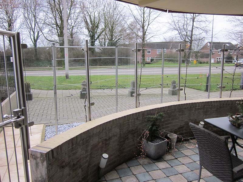 Eine Terrasse mit Tisch und Stühlen und einem Glasgeländer