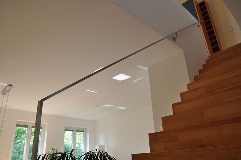 Eine Holztreppe mit Glasgeländer in einem Wohnzimmer