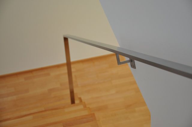 Ein Handlauf an einer Holztreppe in einem leeren Raum.