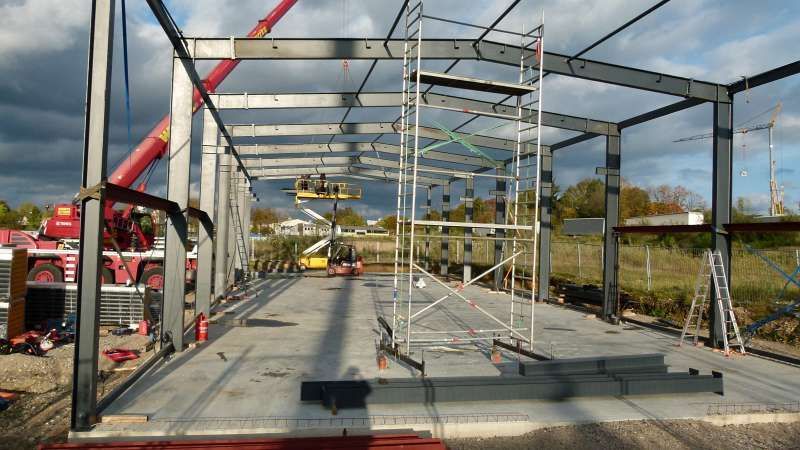 Ein im Bau befindliches Gebäude mit Gerüst und einem Kran im Hintergrund.