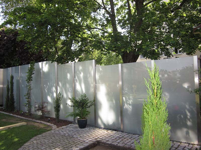 Ein weißer Glaszaun mit Bäumen im Hintergrund