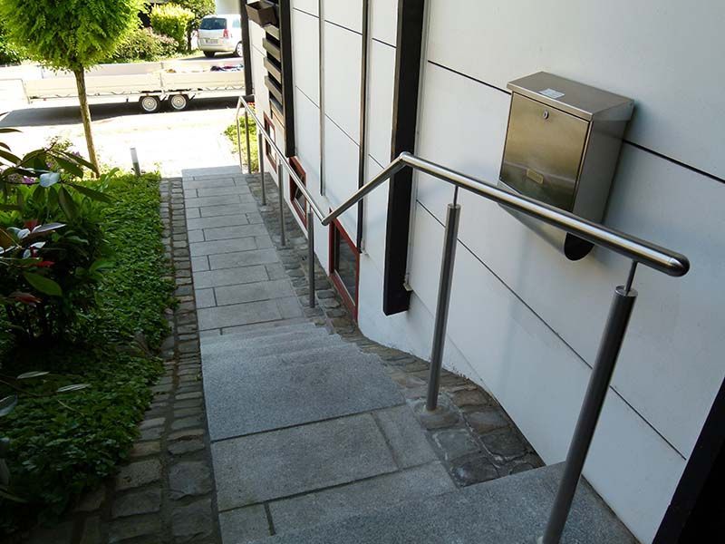 Treppe hinauf zu einem Gebäude mit einem Edelstahlgeländer