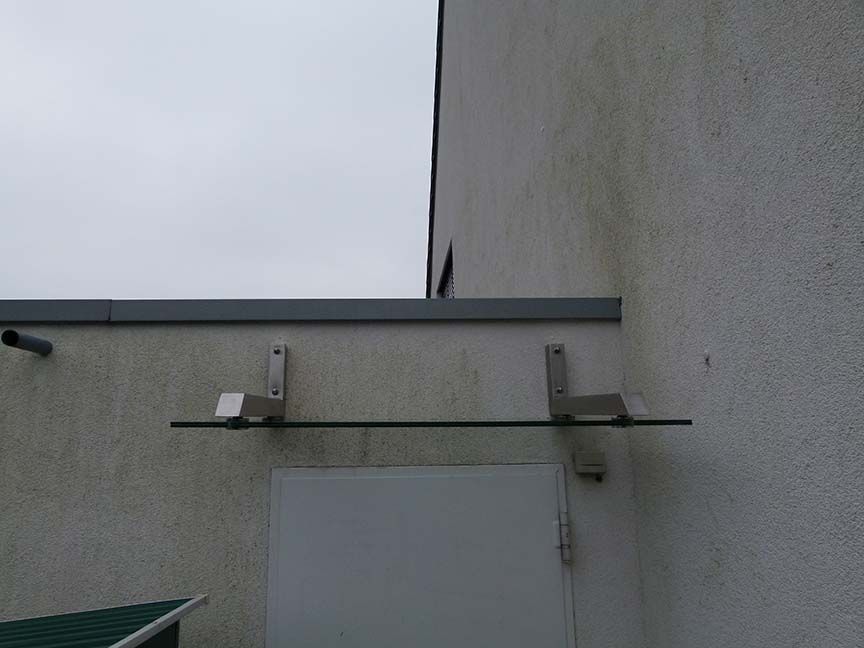 Ein weißes Gebäude mit einem Glasdach über einer Tür.