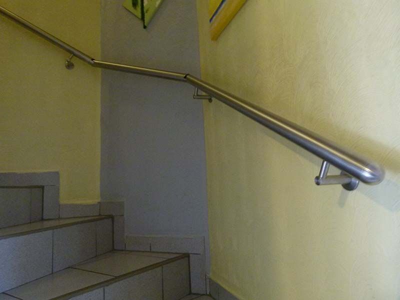 Eine Treppe mit einem Edelstahlgeländer und einer gelben Wand