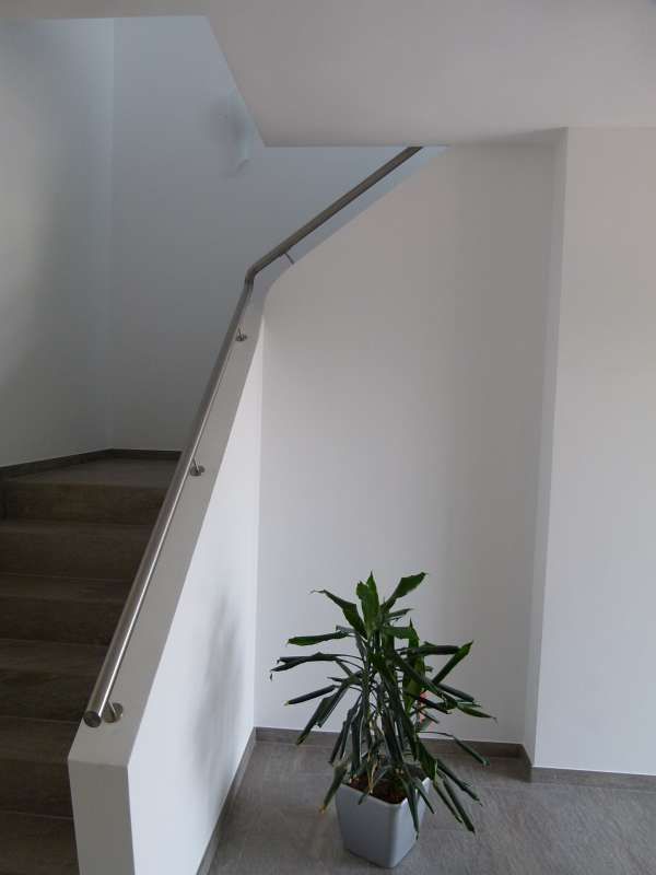 Eine Topfpflanze steht auf dem Boden neben einer Treppe.