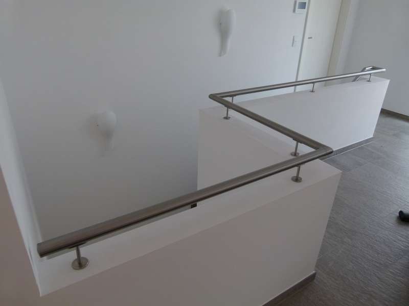 Eine Treppe mit Edelstahlgeländer und weißer Wand.